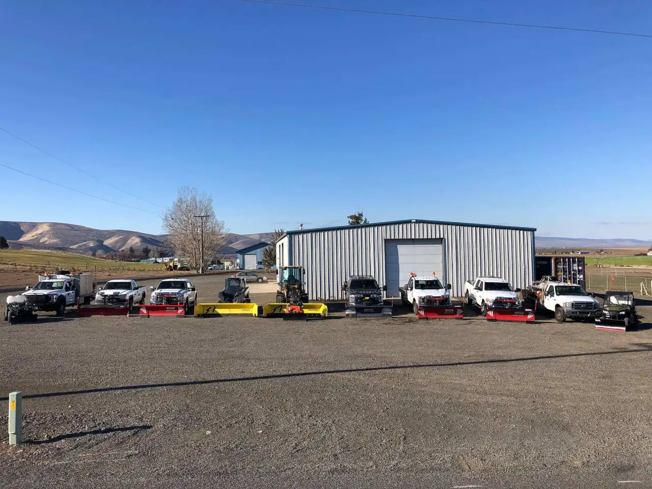 Crystal Clear plow trucks and loaders lined up outside the shop