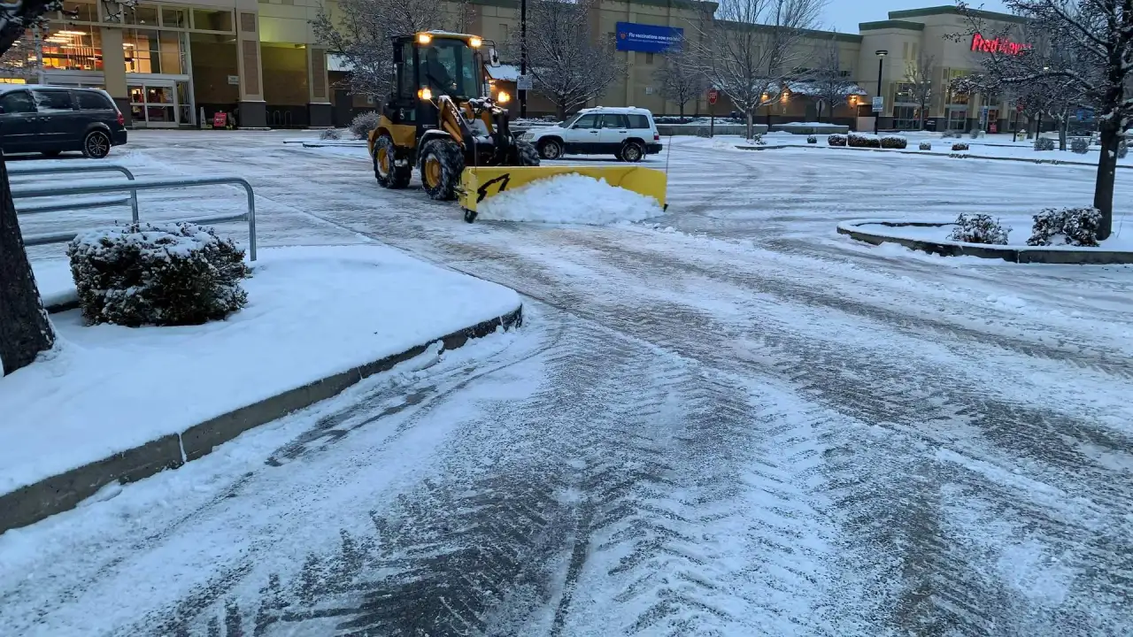 Crystal Clear loader pushing snow in a shopping center parking lot