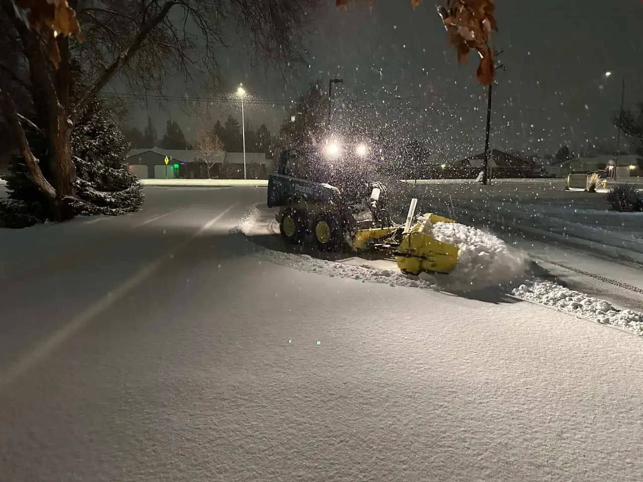 Crystal Clear loader plowing a road at night during a snowfall