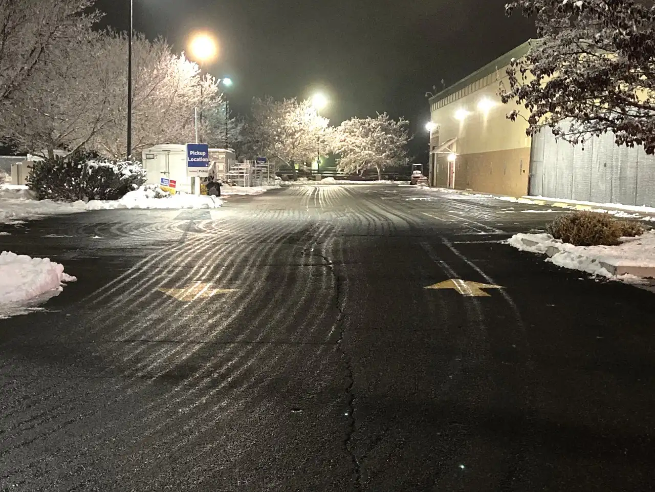 Parking lot at night with streaks of liquid pre-treatment across the pavement